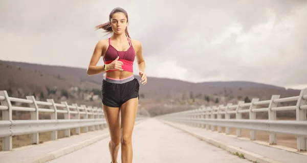 多云的日子里 女运动员在一座桥上跑步 — 图库照片