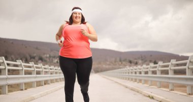 Bulutlu bir günde koşan şişman genç bir kadın.