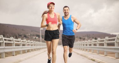 Genç adam ve kadın bulutlu bir günde koşuyorlar