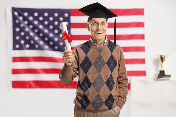 Aufgeregter Senior Mit Diplomhut Und Diplom Posiert Vor Einer Flagge — Stockfoto