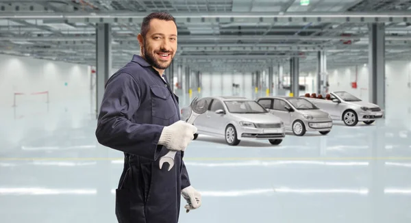 Automechaniker Mit Einem Schraubenschlüssel Vor Fahrzeugen Einer Garage — Stockfoto