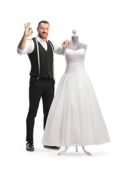裁缝站在穿着洋娃娃人偶的婚纱旁边 给一个白色背景的孤身一人做手势 — 图库照片