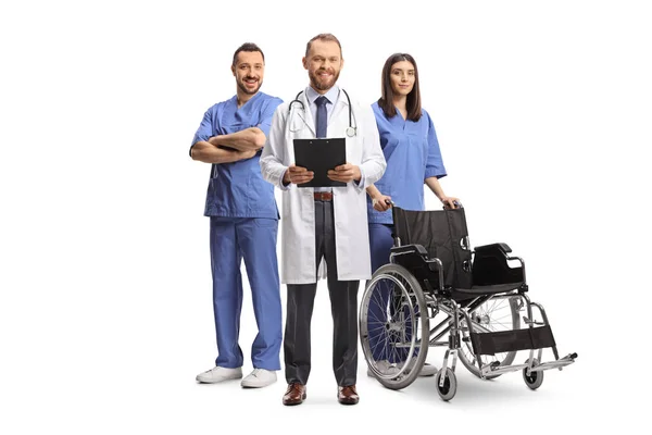 車椅子の青い制服を着た医療従事者と白い背景に隔離されたクリップボードを保持する男性医師 — ストック写真