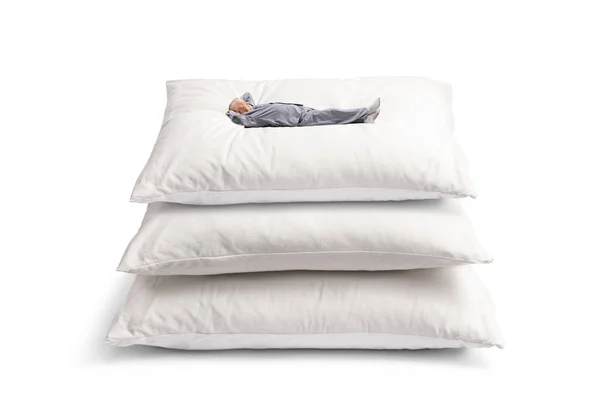 穿着睡衣的成熟男人躺在一堆靠白背衬的枕头上 — 图库照片