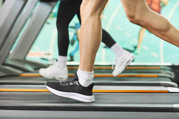 ジムのトレッドミルで走る男性と女性の足のショット — ストック写真