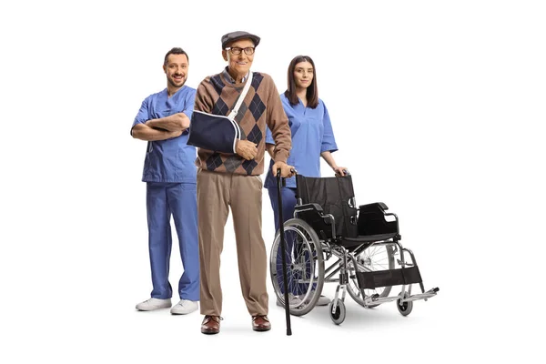 白地に隔離された高齢者の負傷した男性患者の後ろに車椅子を持つ男性と女性看護師 — ストック写真