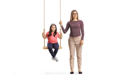 Anne, beyaz arka planda izole edilmiş bir salıncakta kızın yanında duruyor.