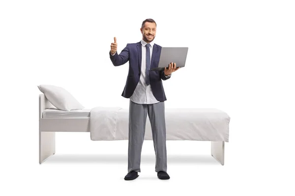 スーツを着たビジネスマンとノートパソコンを持ち白い背景に隔離された親指をジェスチャー — ストック写真