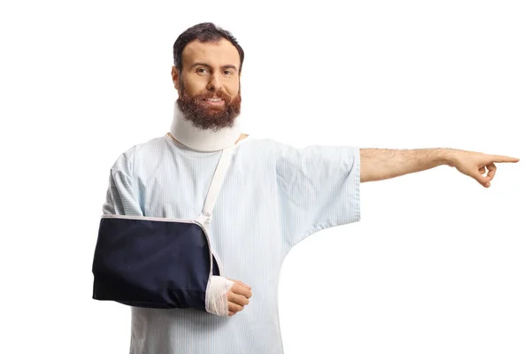 白い背景に隔離された側面を指す腕のスリングと子宮頸部の襟を持つ男性患者 — ストック写真