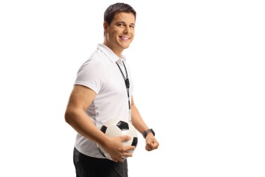 Futbol koçu bir top tutuyor ve gülümsüyor.