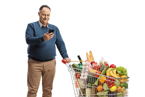 Dojrzały Mężczyzna Wózkiem Zakupy Patrząc Jego Smartfon Odizolowany Białym Tle — Zdjęcie stockowe
