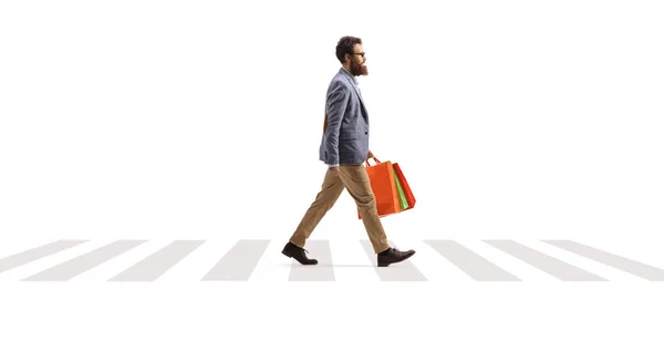 白い背景に隔離された横断歩道で買い物袋を持っている髭の男の完全な長さのプロフィールショット — ストック写真