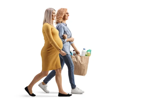 妊娠中の女性を助け 白い背景に隔離された食料品袋を運ぶ女性の完全な長さのプロフィールショット — ストック写真
