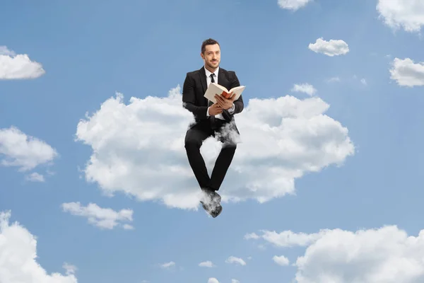 Geschäftsmann Sitzt Auf Einer Wolke Mit Einem Buch Der Hand — Stockfoto