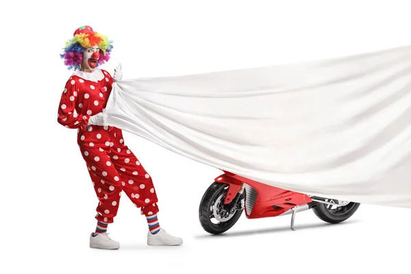 白い背景に隔離された赤いオートバイの前で大きな白い布を引くクラウン — ストック写真