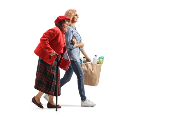 女性の完全な長さのプロフィールショット高齢者の女性を支援し 白い背景に隔離された食料品袋を運ぶ — ストック写真