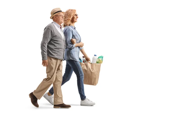 女性のフル長さプロフィールショットの女性を助ける高齢者男性と運ぶ食料品袋隔離された白い背景 — ストック写真