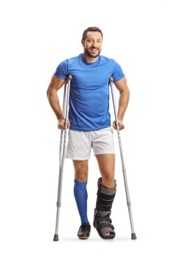 Koltuk değnekleri ve beyaz arka planda izole edilmiş yürüyen bir desteğe sahip bir erkek sporcunun tam boy portresi.