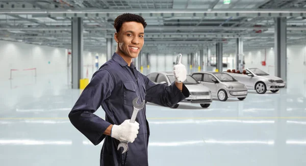非洲裔美国人汽车修理工手握扳手 在车架内竖起大拇指作手势 — 图库照片