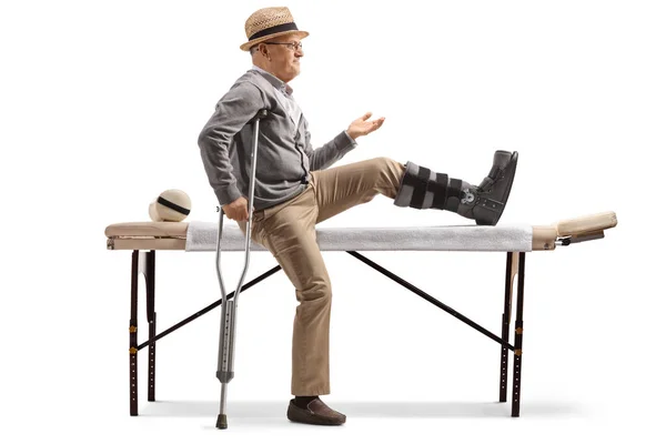Senior Man Met Een Beenbeugel Zittend Een Bed Voor Fysiotherapie — Stockfoto