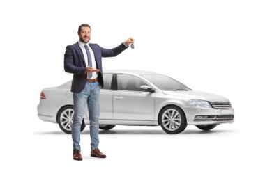 Genç profesyonel bir adam beyaz arka planda izole edilmiş ince bir arabanın önünde araba anahtarı tutuyor.