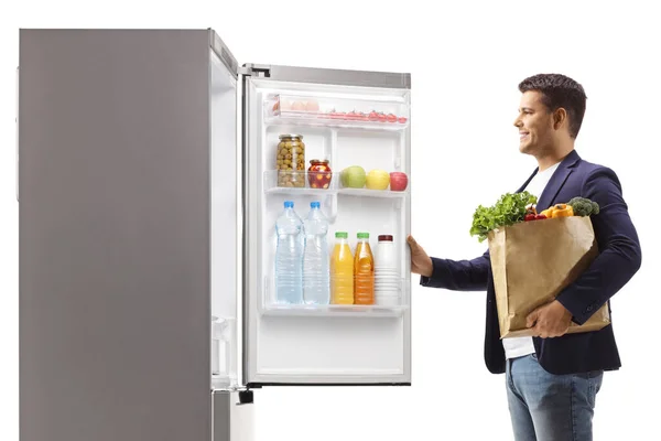 Mann Mit Einkaufstasche Öffnet Kühlschranktür Isoliert Auf Weißem Hintergrund — Stockfoto