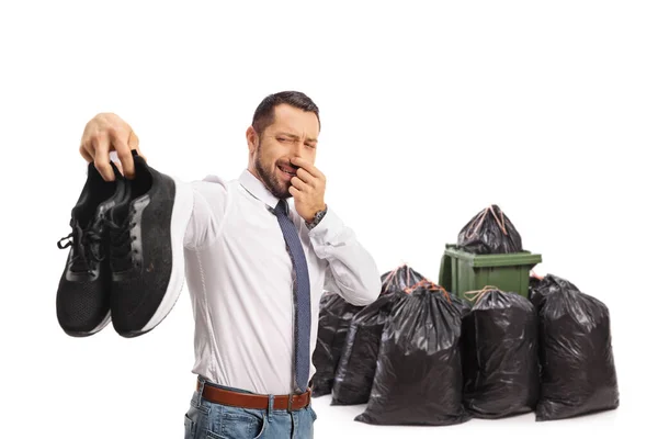 白い背景に隔離されたゴミ箱の前で臭いトレーナーのペアを保持男 — ストック写真