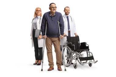 Tekerlekli sandalyeli doktorlar beyaz arka planda koltuk değnekleri olan bir hastanın arkasında duruyorlar.