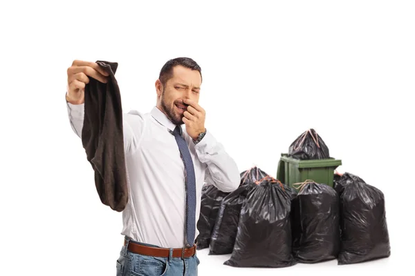 白い背景に隔離されたゴミ箱の前で臭い古い靴下のペアを保持ビジネスマン — ストック写真