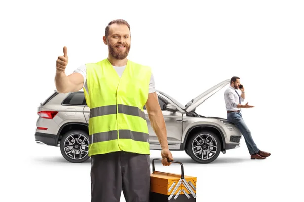 道路支援労働者は車の前に立つ反射ベストで 顧客は白い背景に隔離された電話をかける — ストック写真