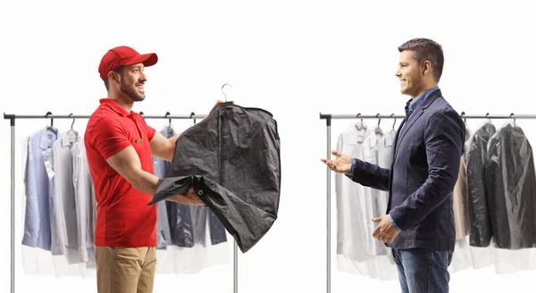 Dry cleaning worker giving a suit on a hanger with a cover to a male customer isolated on a white backgroun