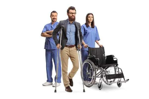 白地に孤立した髭の男の後ろに立つ青い制服を着た男性と女性の医療従事者 — ストック写真