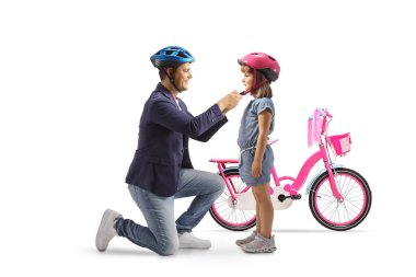 Baba ve kızı kask takıyor ve beyaz arka planda izole edilmiş bir bisiklet yolculuğuna hazırlanıyorlar.