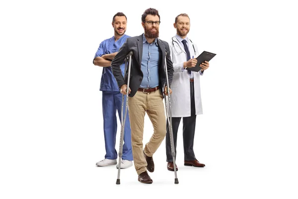 Medicinskt Team Med Manlig Patient Som Står Med Kryckor Isolerade — Stockfoto