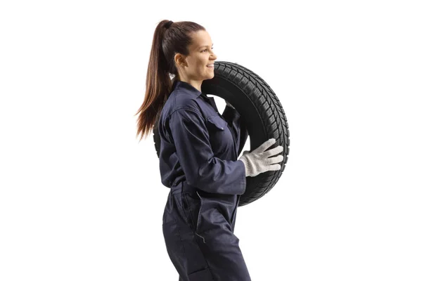 一名女汽车修理工背着车胎 在白色背景下独立行走的侧面照片 — 图库照片