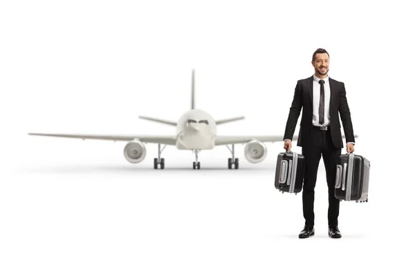 スーツケースを携帯し 白い背景に隔離された平面の前に立つビジネスマンの完全な長さの肖像画 — ストック写真