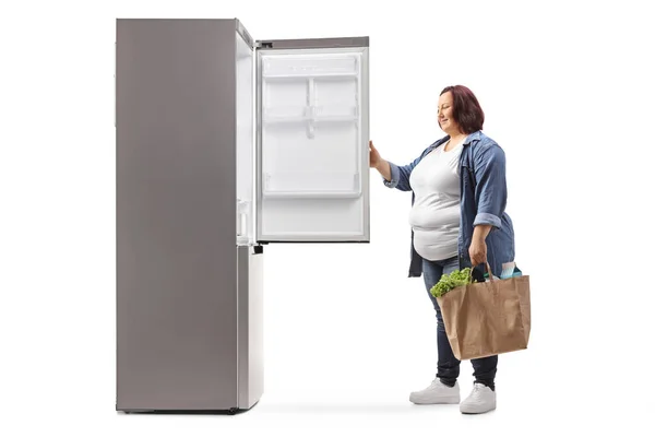 Übergewichtige Junge Frau Mit Einkaufstaschen Öffnet Einen Kühlschrank Isoliert Auf — Stockfoto