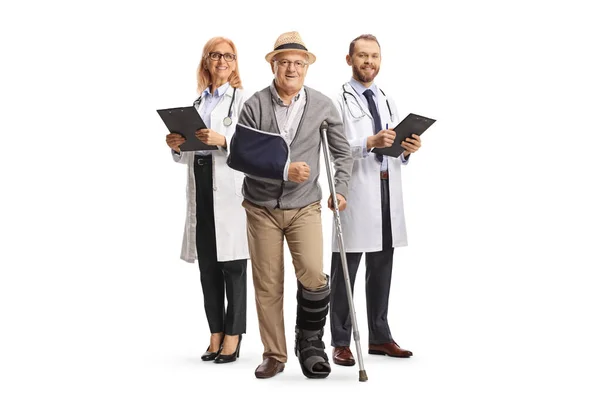 白い背景に隔離された背中に松葉杖と医師を持つ高齢男性患者の完全な長さの肖像画 — ストック写真