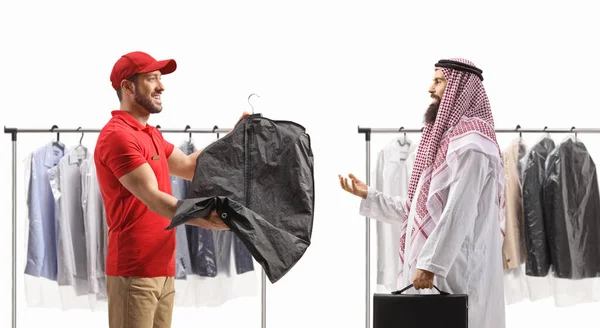 Man delivering dry cleaning clothes to an arab man in ethnic clothes isolated on a white backgroun