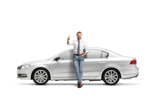 銀の車にもたれかかっている男の完全な長さの肖像画とジェスチャー親指アップ白の背景に隔離 — ストック写真