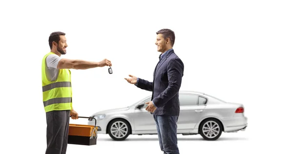 白い背景に隔離された男に車の鍵を与える道路のヘルプエージェント — ストック写真