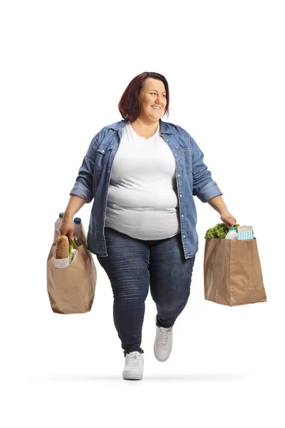 太りすぎの若い女性を運ぶ食料品袋歩くと白の背景に隔離された側を見て — ストック写真
