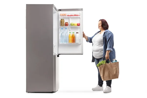 Übergewichtige Frau Mit Einkaufstaschen Öffnet Einen Kühlschrank Isoliert Auf Weißem — Stockfoto