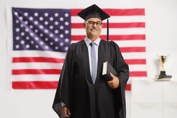 Gammal Man Examensklänning Med Bok Framför Amerikansk Flagga — Stockfoto