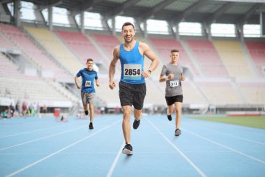 Stadyumda yarış yapan erkeklerin uzun bir portresi. 