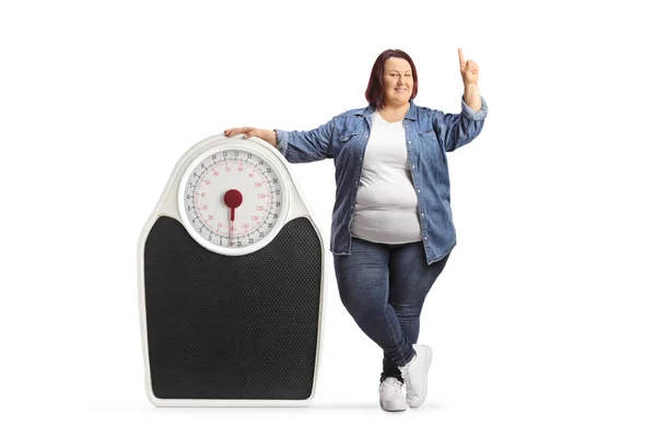 Overgewicht Vrouw Staan Naast Een Medische Schaal Wijzen Omhoog Geïsoleerd — Stockfoto