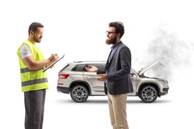 Yol kenarında yardım görevlisi ve beyaz arka planda izole edilmiş kırık bir arabası olan bir adam.