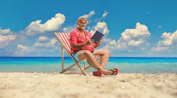 一个成熟的男性游客 带着一本书坐在海边的长椅上 — 图库照片