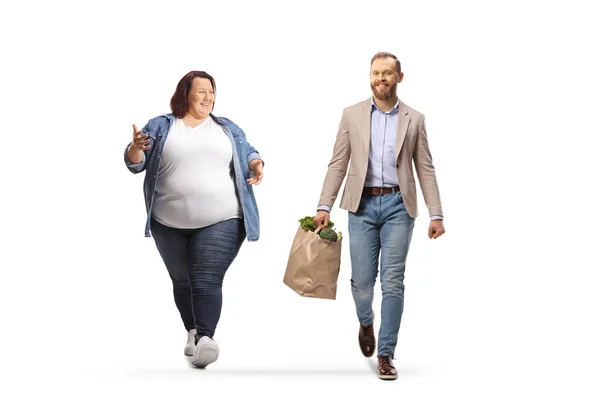 腐敗した女と食料品袋を持った男が歩いて白地に隔離された会話をしている — ストック写真