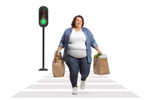 胖女人 提着购物袋穿过一条被白色背景隔离的街道 — 图库照片